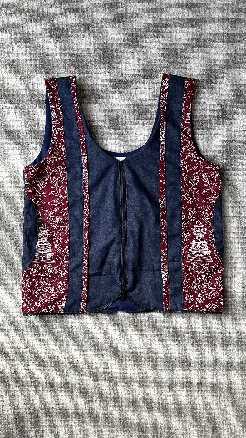 Vest denim navy Seri Laras dengan panel batik maroon bermotif candi dan flora, tampak depan